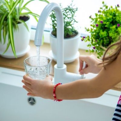 Child filling glass with water from kitchen tap